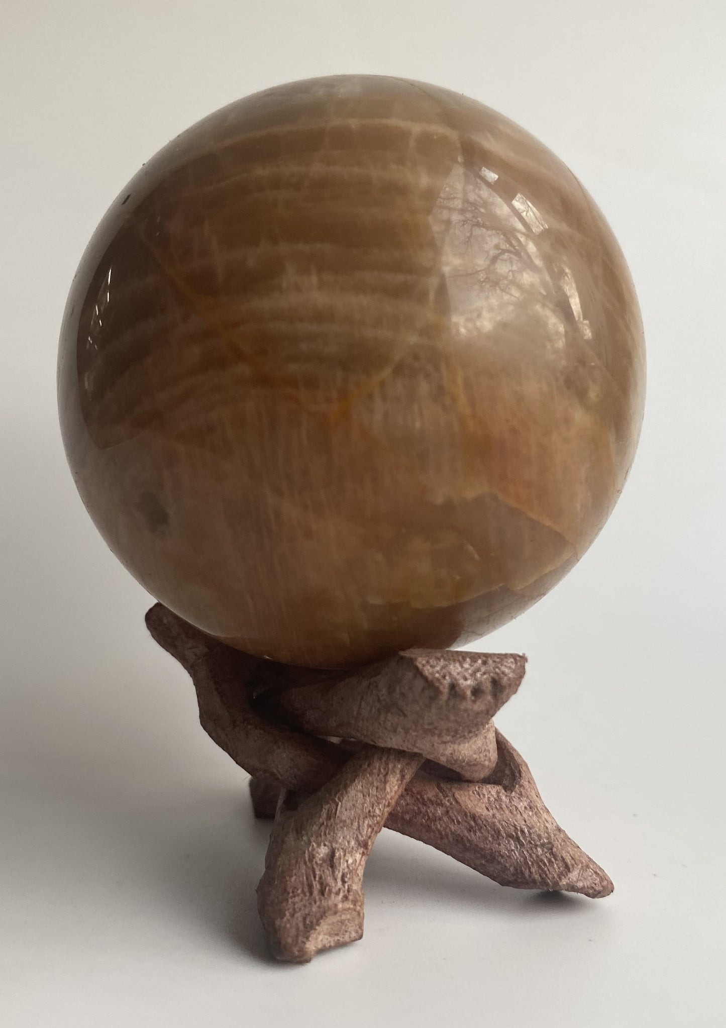 Sfera din mineral de piatra lunii pe suport din lemn, pe fundal alb sub lumina naturala