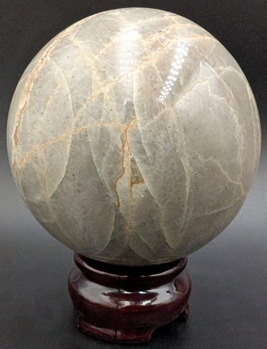 Sfera din piatra semipretioasa de piatra lunii verde pe suport din lemn cu fundal negru