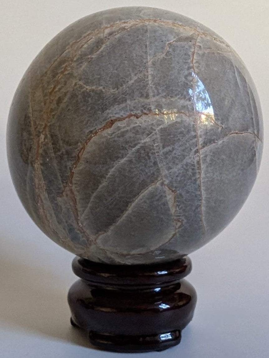 Sfera de 7.1cm din piatra semipretioasa de piatra lunii verde pe suport din lemn cu fundal alb