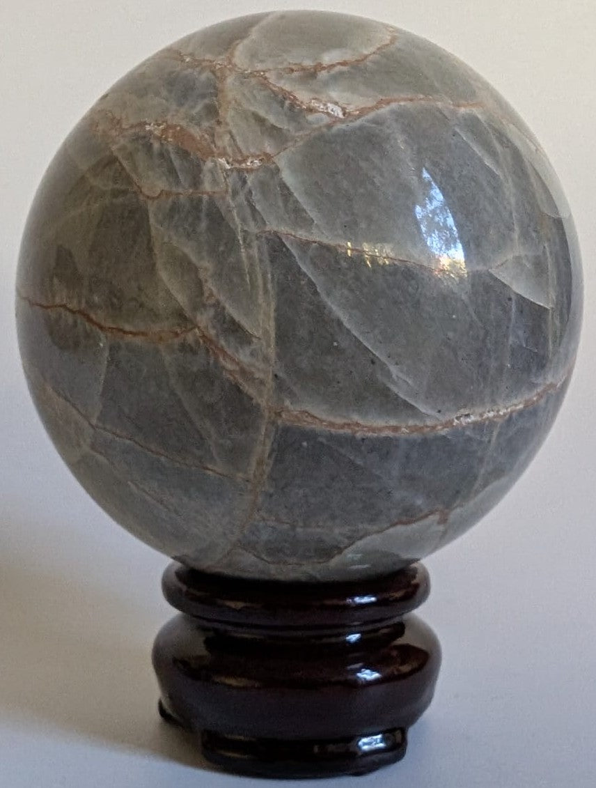 Sfera de 7.1cm din cristal de piatra lunii verde pe suport din lemn cu fundal alb