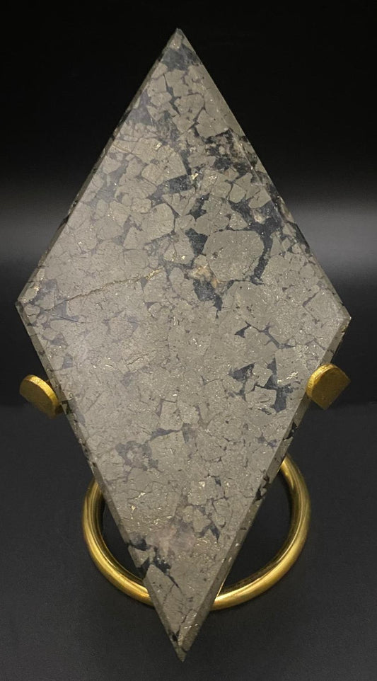 Romb din mineral de pirita cu suport metalic auriu pe fundal negru sub lumina artificiala