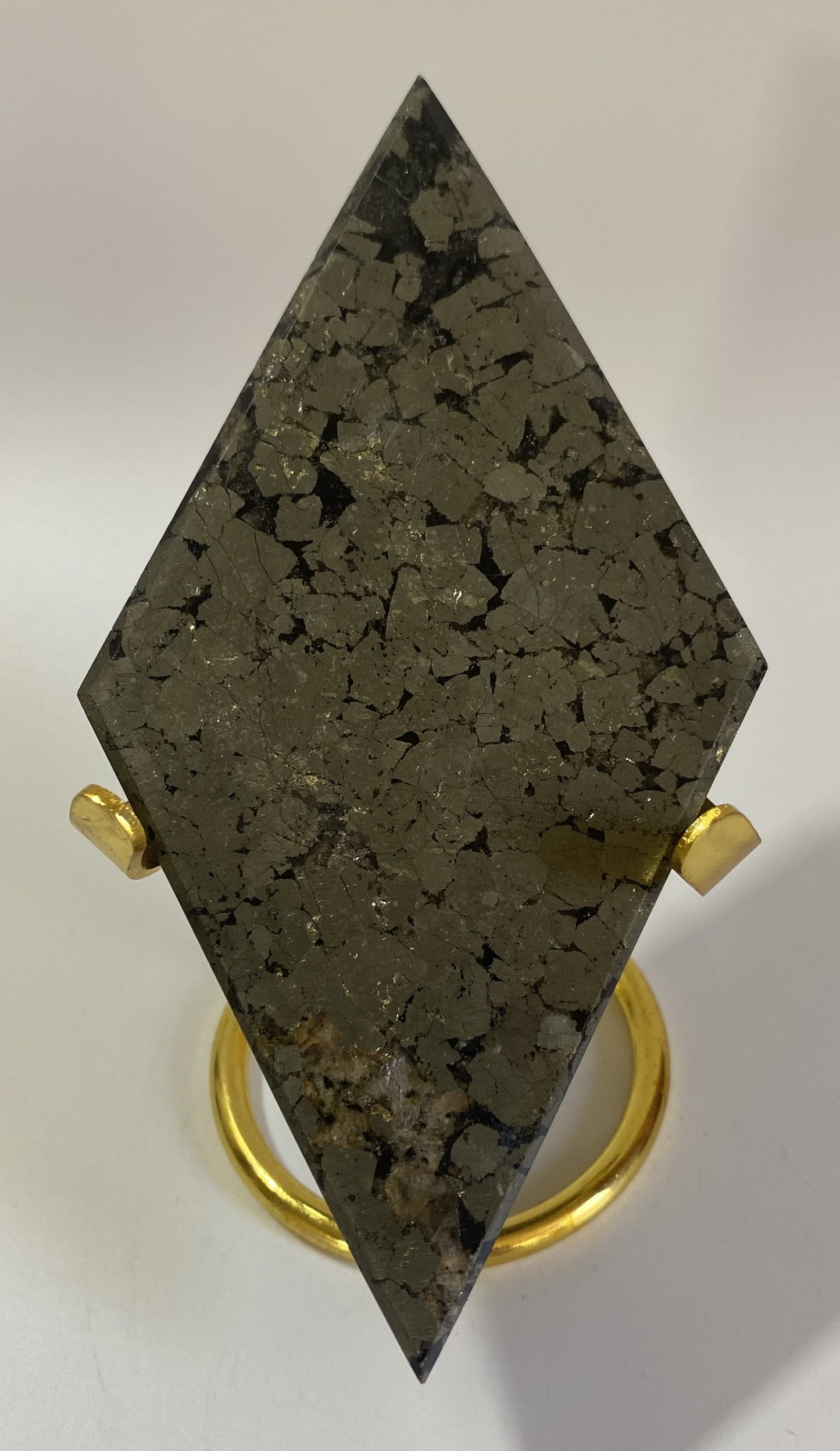 Romb din mineral de pirita cu suport metalic auriu pe fundal alb sub lumina naturala