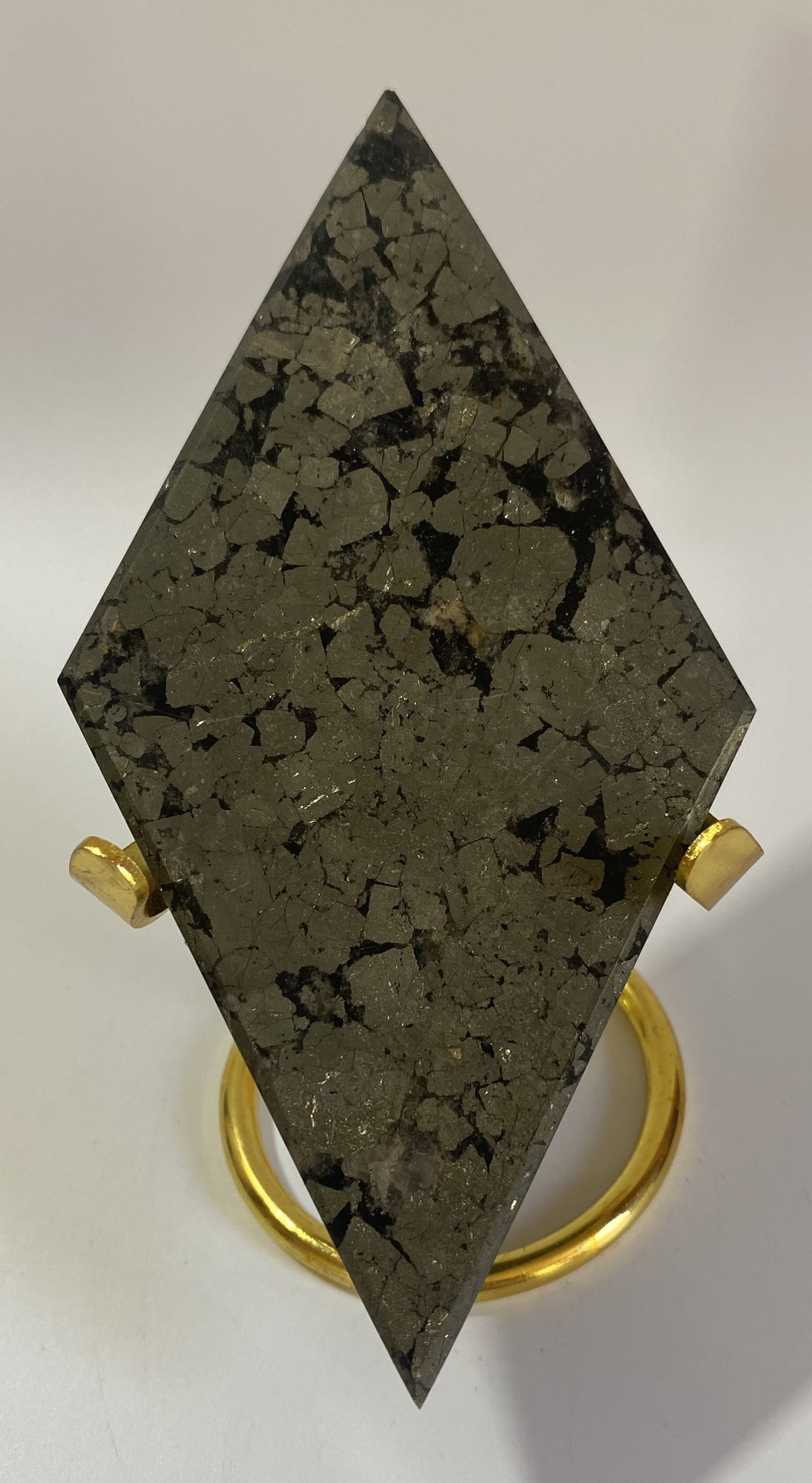 Romb din mineral de pirita cu suport metalic auriu pe fundal alb sub lumina naturala