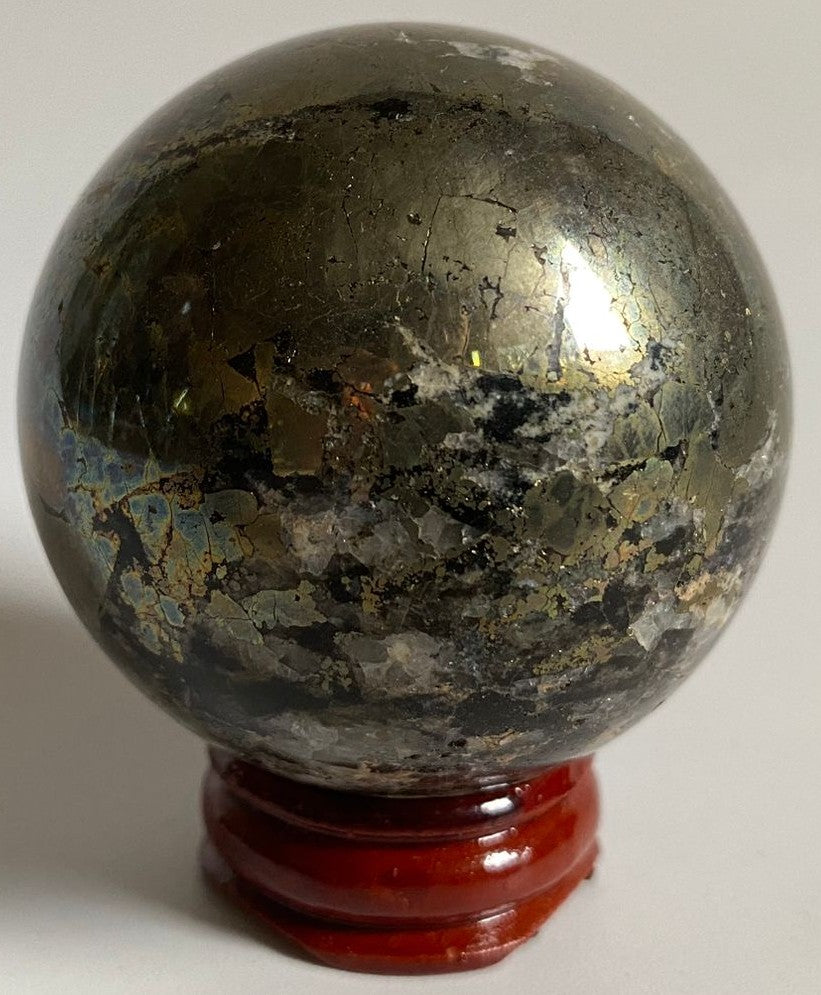 Sfera din cristal de pirita pe suport din lemn cu fundal alb