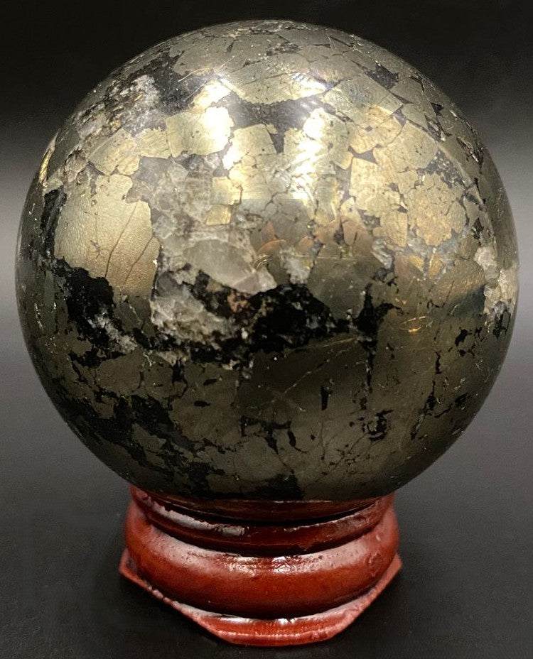 Sfera din piatra semipretioasa de pirita pe suport din lemn cu fundal negru