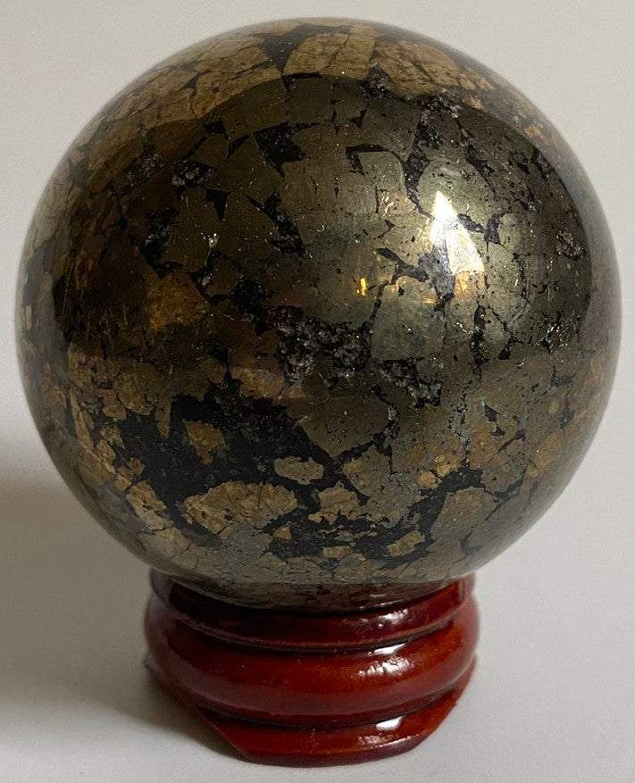 Sfera din cristal de pirita pe suport din lemn cu fundal alb