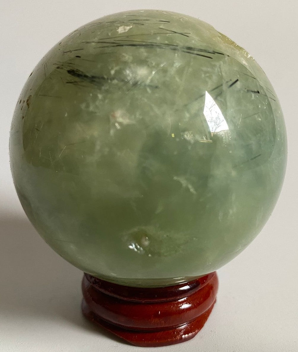 Sfera din cristal de prehnit pe suport din lemn cu fundal alb