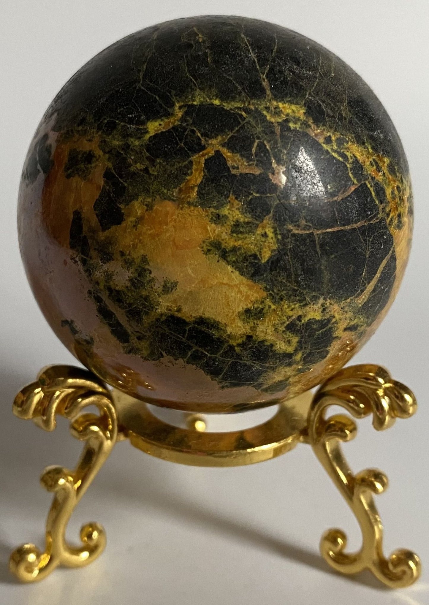 Sfera din cristal de realgar pe suport din metal cu fundal alb