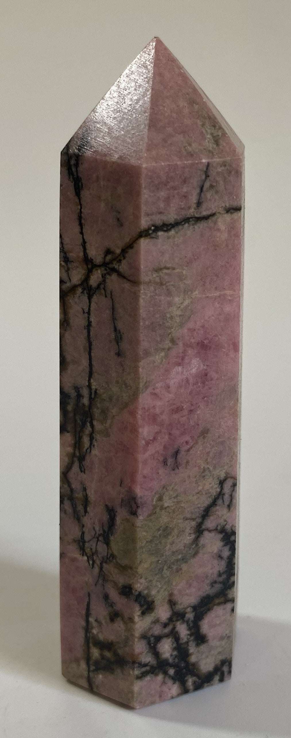 Rodonit obelisk din piatra semipretioasa cu texturi negre pe fundal roz