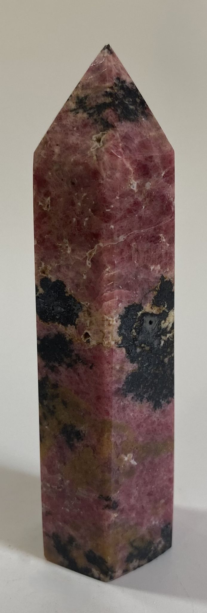 Obelisc din cristal de rodonit pe fundal alb