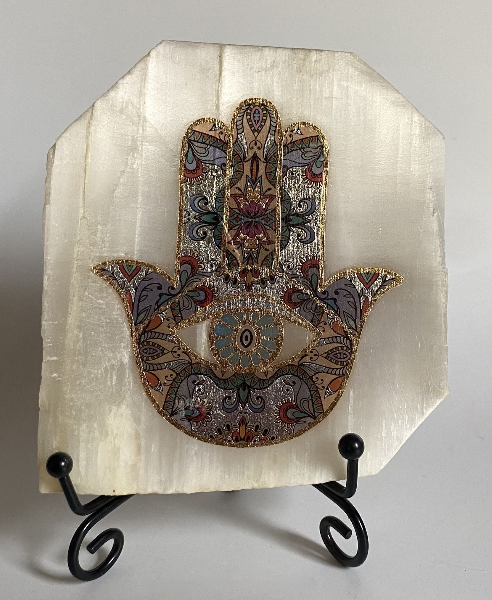Decoratiune naturala felie de selenit imprimata cu talisman Hamsa pe suport metalic si fundal alb