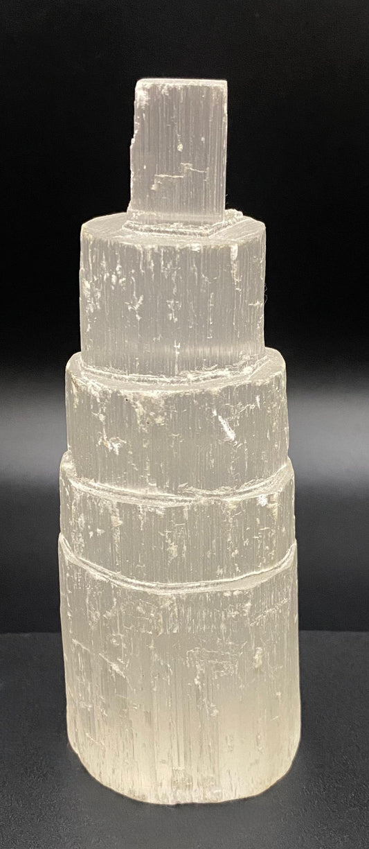 Obelisc turn din mineral de selenit pe fundal negru sub lumina artificiala