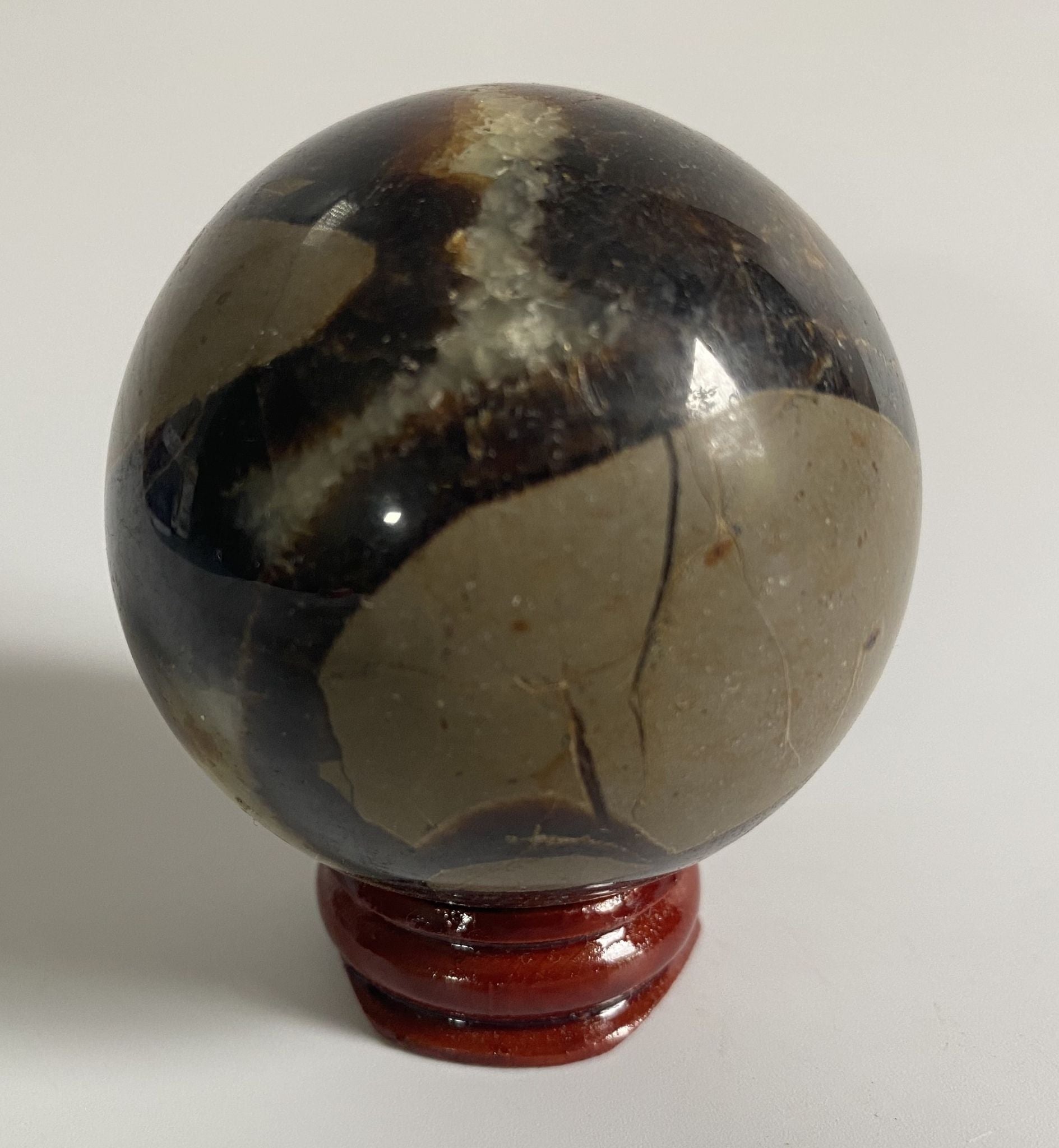 Sfera din cristal de septaria pe suport din lemn cu fundal alb