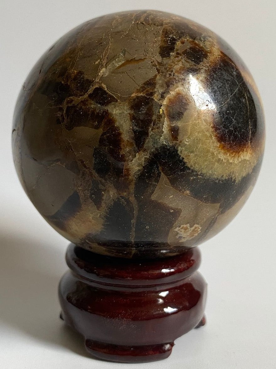 Sfera din cristal de septaria pe suport din lemn cu fundal alb