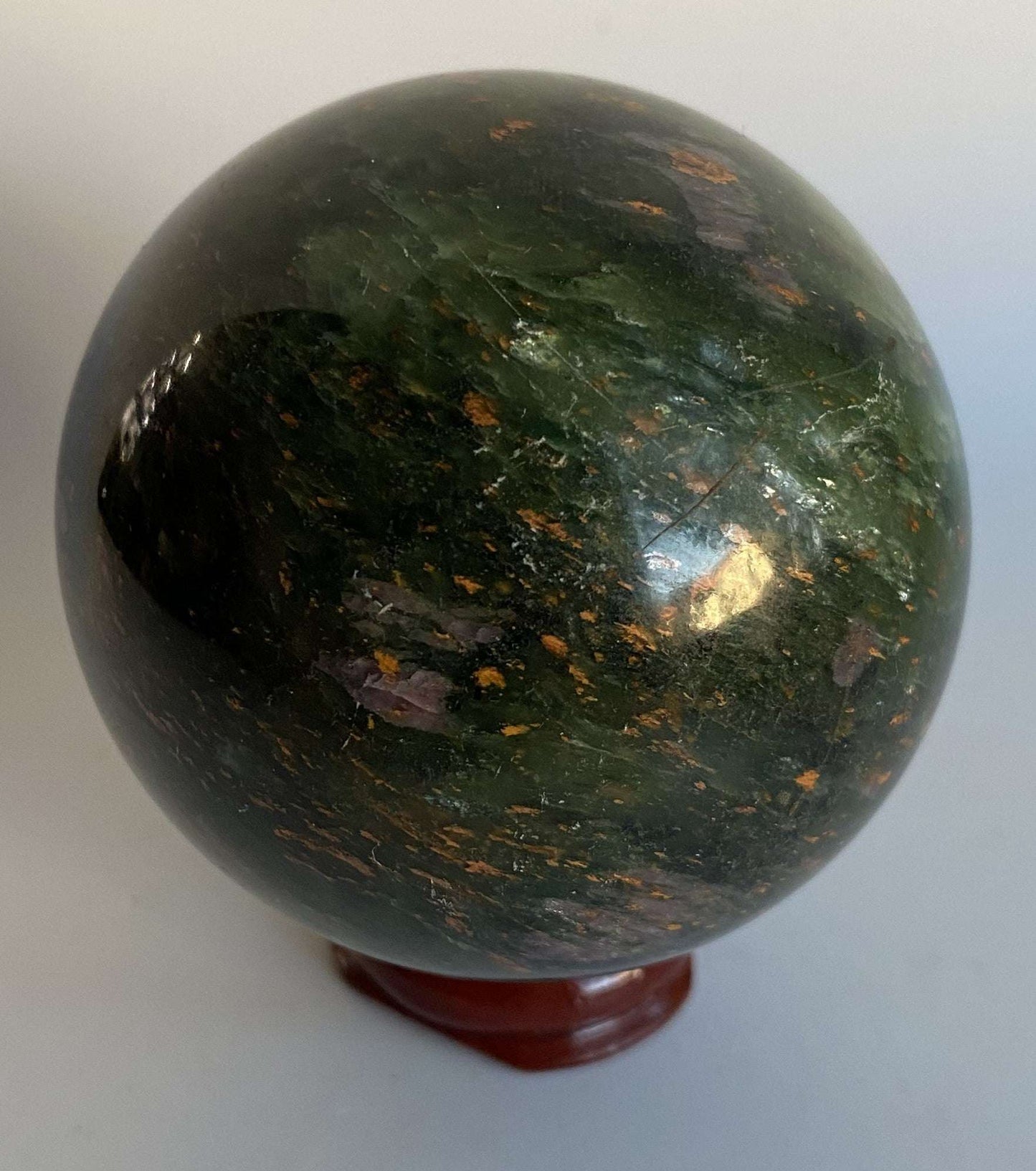 Green Corindon in Zoisit gemstone sphere with natural pink-violet floral patterns on wooden stand