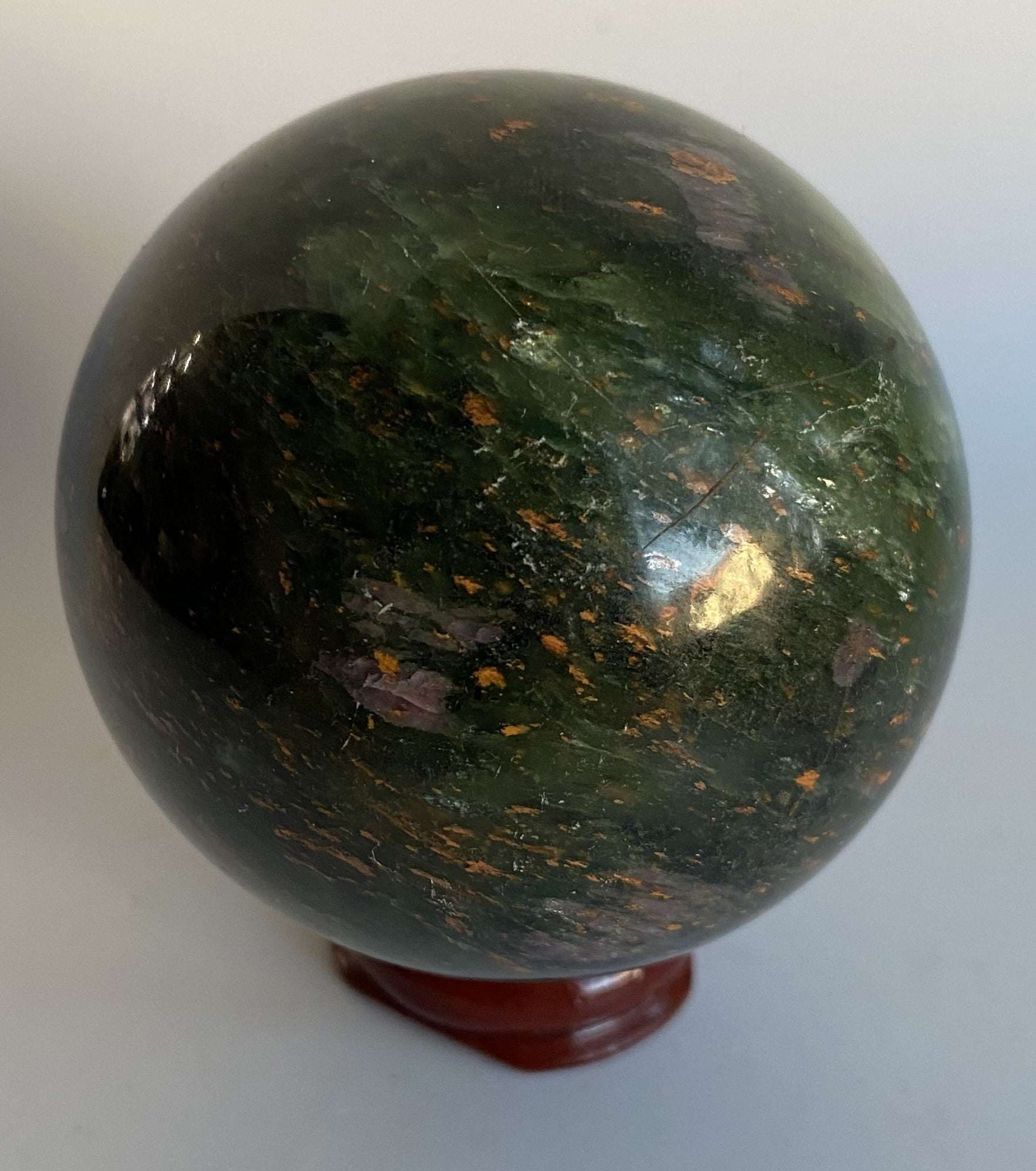 Green Corindon in Zoisit gemstone sphere with natural pink-violet floral patterns on wooden stand
