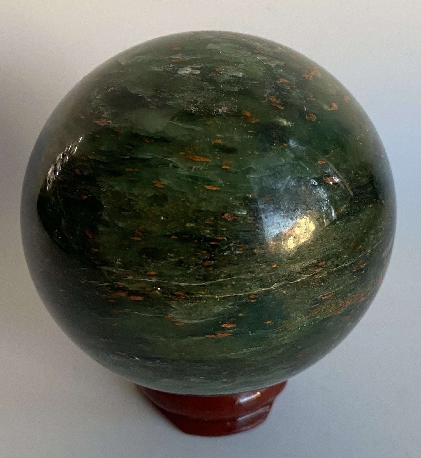 Green Corindon in Zoisit gemstone sphere on wooden stand with natural floral patterns