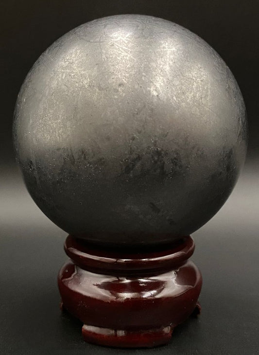 Sfera din piatra semipretioasa de shungit pe suport din lemn cu fundal negru