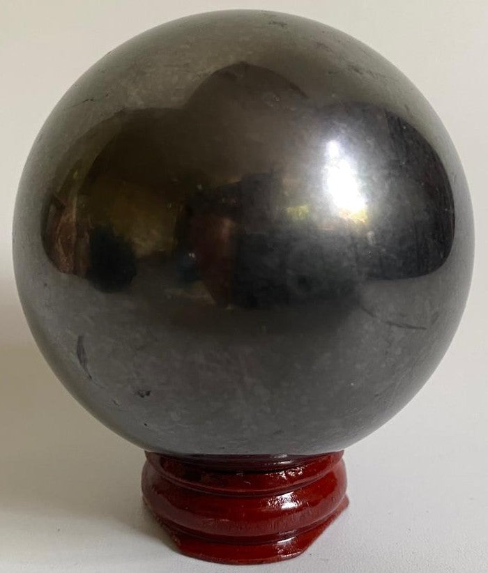 Sfera din cristal de shungit pe suport din lemn cu fundal alb