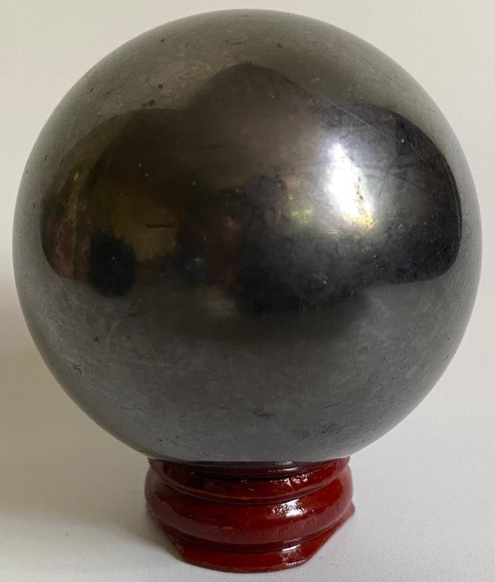 Sfera din mineral de shungit pe suport din lemn cu fundal alb