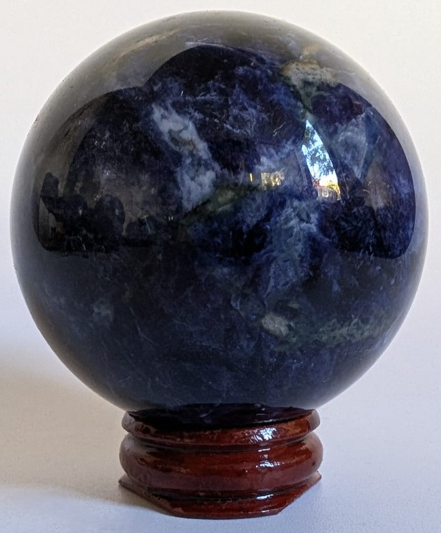 Sfera din cristal de sodalit pe suport din lemn cu fundal alb
