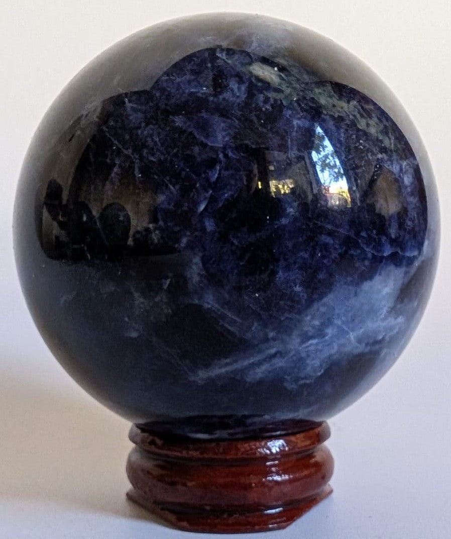 Sfera de 5.7cm din cristal de sodalit pe suport din lemn cu fundal alb