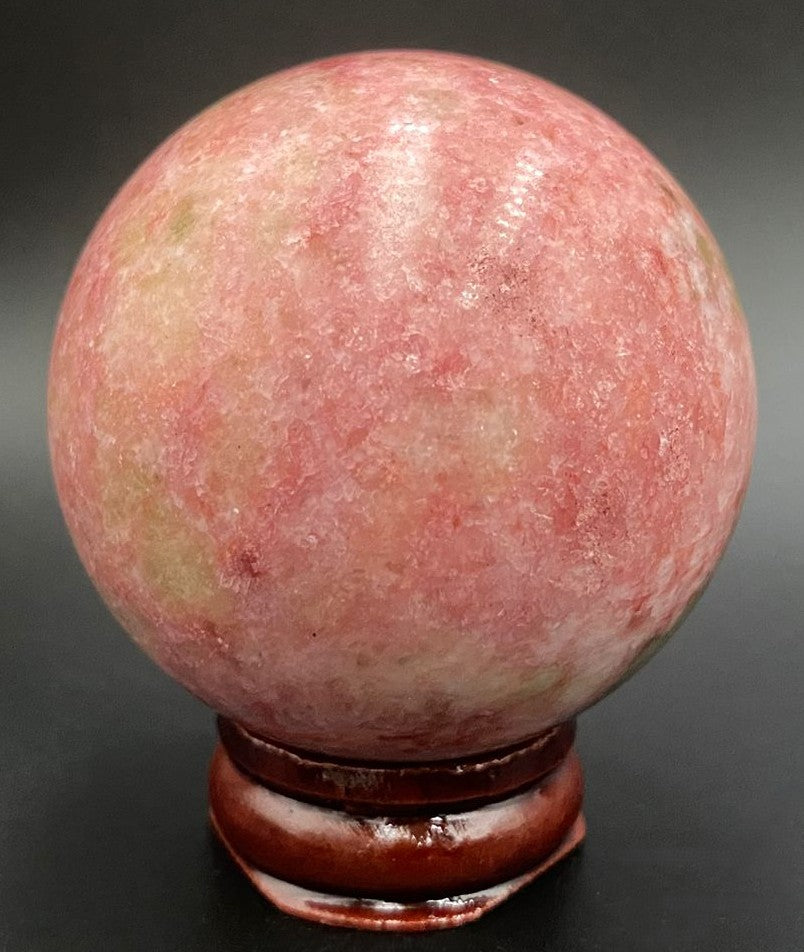 Sfera din piatra semipretioasa de thulit pe suport din lemn cu fundal negru