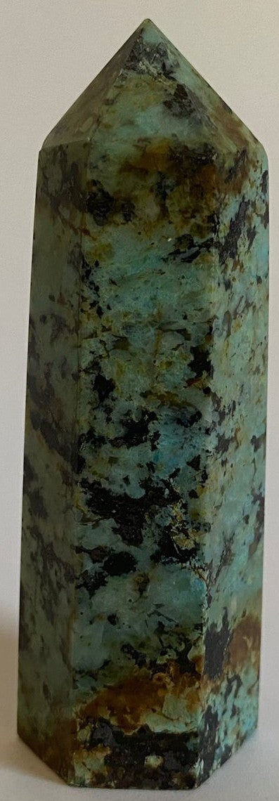 Obelisc din cristal de turcoaz verde pe fundal alb