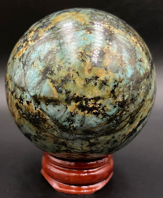 Sfera din piatra semipretioasa de turcoaz verde pe suport din lemn cu fundal negru