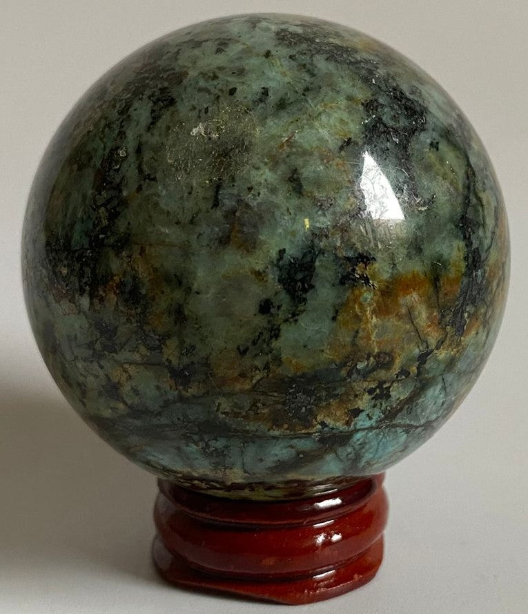 Sfera din cristal de turcoaz verde pe suport din lemn cu fundal alb