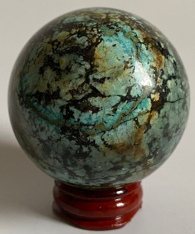 Sfera din cristal de turcoaz verde pe suport din lemn cu fundal alb
