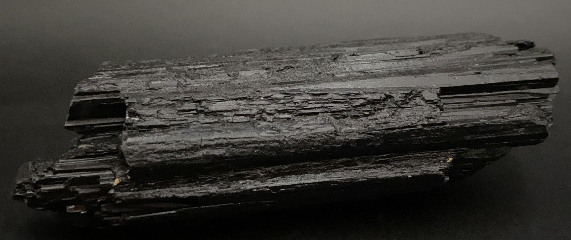 Cristal de piatra bruta din turmalina neagra pe fundal negru