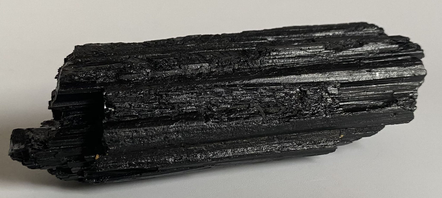 Cristal de piatra bruta din turmalina neagra pe fundal alb