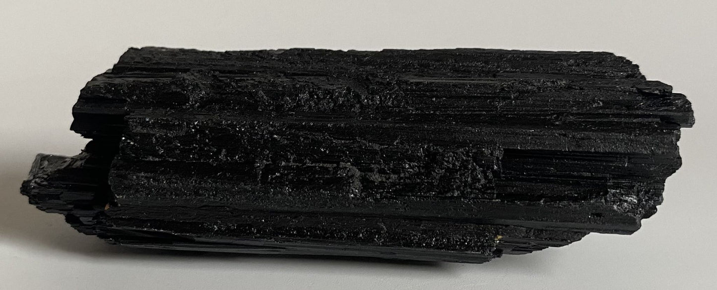 Piatra semipretioasa bruta din turmalina neagra pe fundal alb