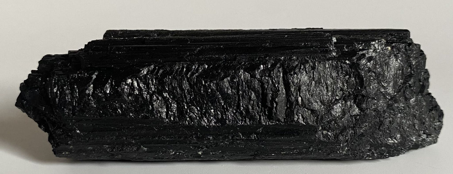 Piatra bruta din turmalina neagra pentru meditatie pe fundal alb