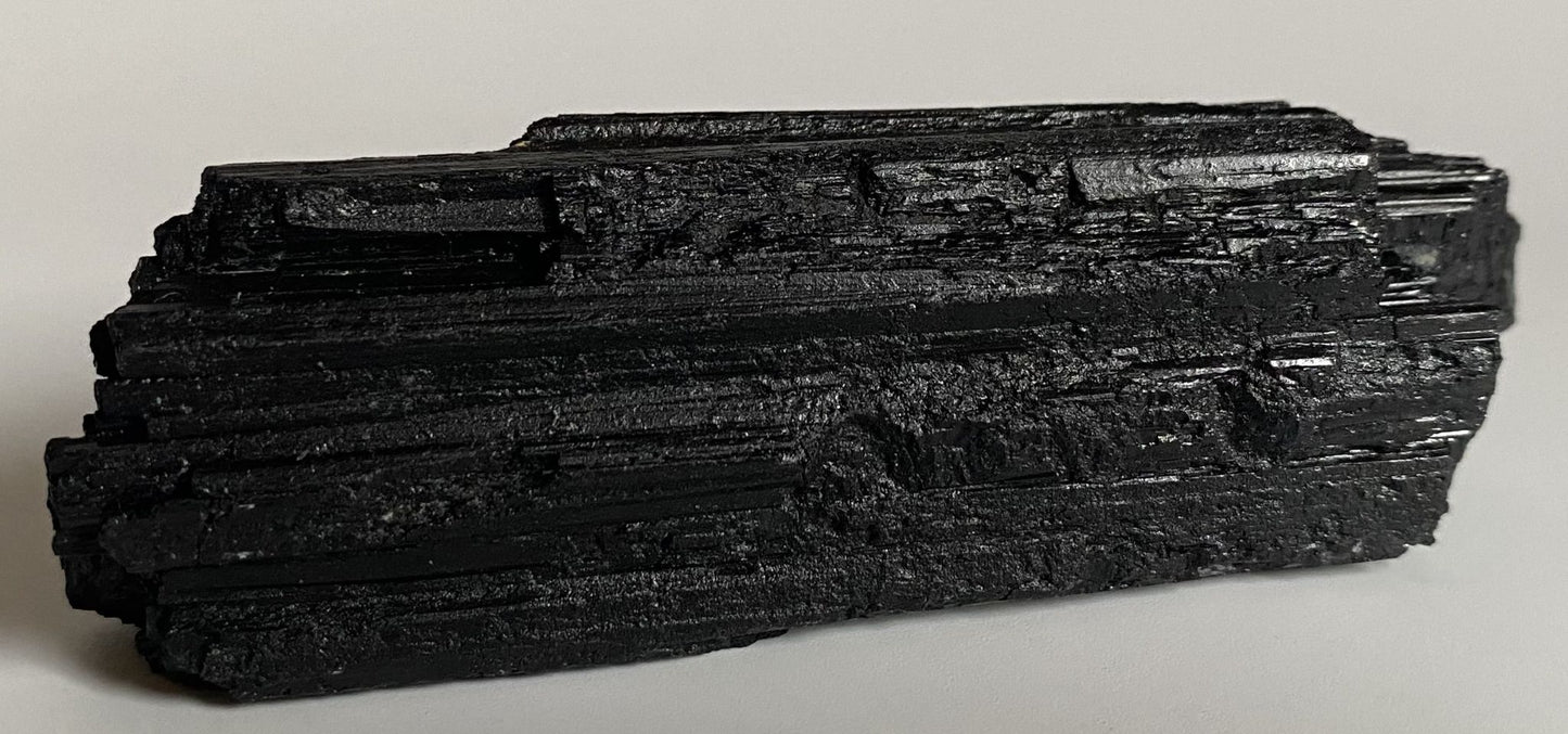 Cristal din piatra bruta din turmalina neagra pentru meditatie pe fundal alb