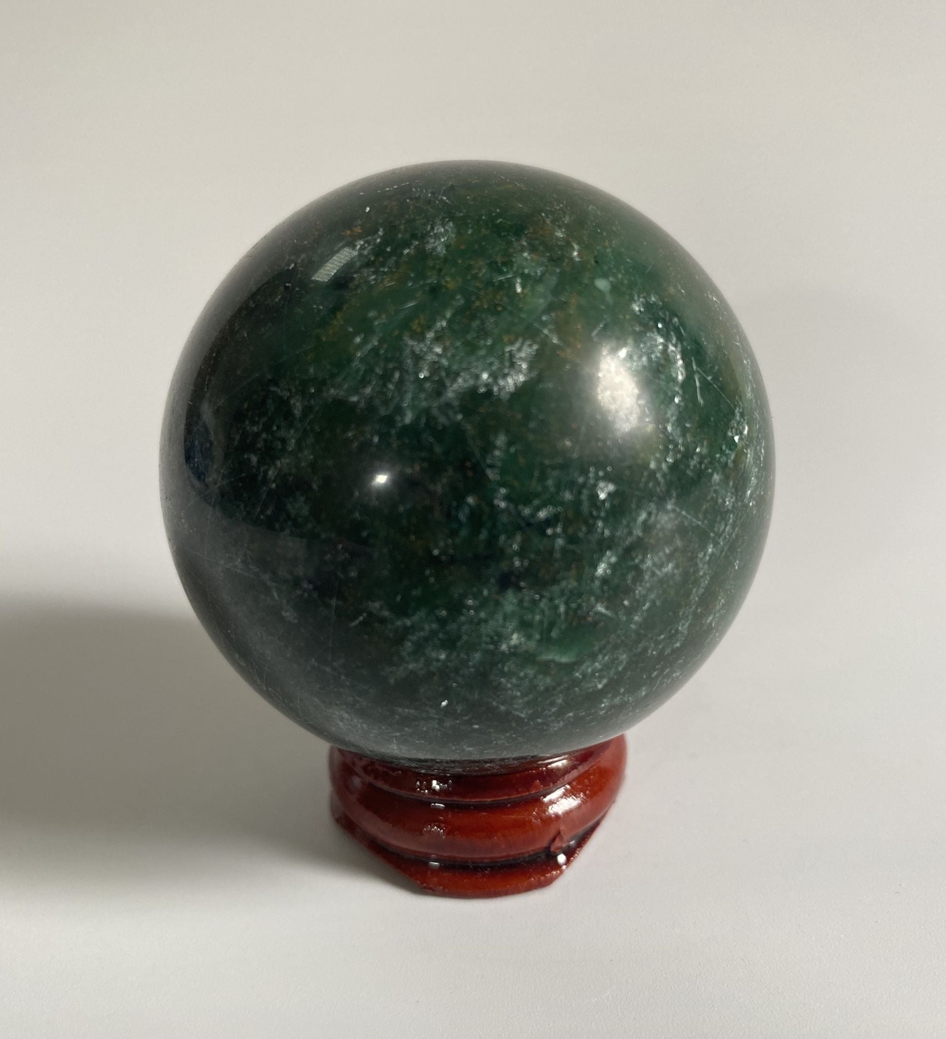 Sfera din cristal de verdit pe suport din lemn cu fundal alb
